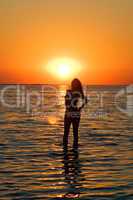 Silhouette of the young woman on a gulf on a sunset