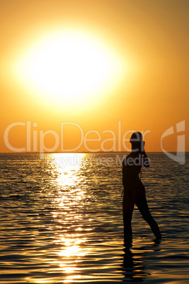 Silhouette of the young woman on a bay on a sunset