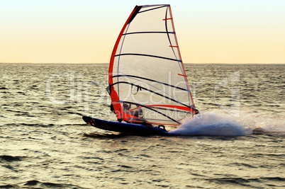 Silhouette of a windsurfer on a gulf, moving at great speed
