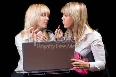 Two blondes do makeup in front of the laptop screen. Isolated