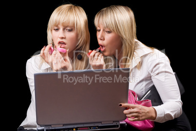 Two blondes do makeup in front of the laptop screen