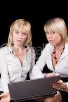 Two businesswomen with laptop. Isolated on black background