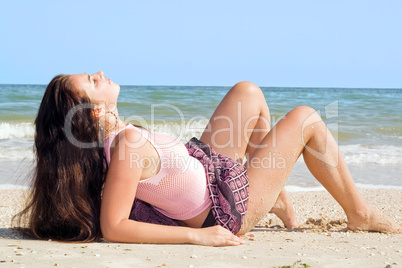 The beauty young woman lies on sand at sea coast