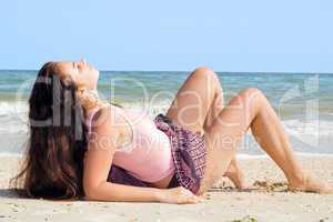 The beauty young woman lies on sand at sea coast