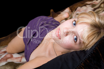 The young beautiful blonde lies on a bed
