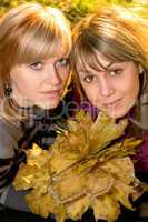 Portrait of the two young blonde with autumn leaves