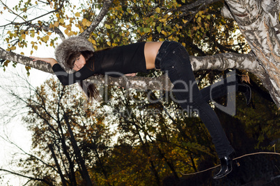 The young woman hanging on a birch branch. A funny picture