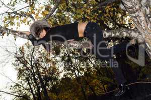 The young woman hanging on a birch branch. A funny picture