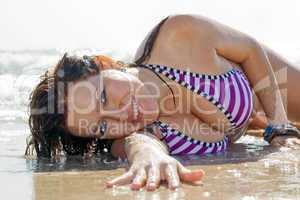 The young woman lies in waves on sea coast