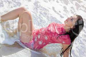 The beautiful young woman lies in waves on sea coast