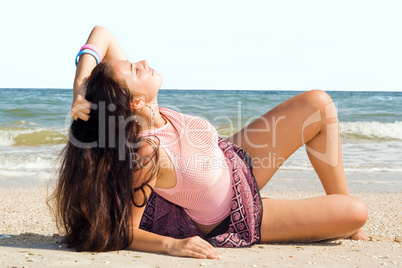The young woman lies on sand at sea coast