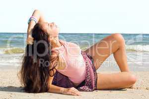 The young woman lies on sand at sea coast