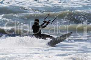 Silhouette of kite surfer jumping over the waves