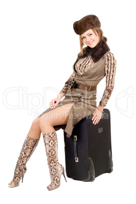 Young lady sits on a suitcase. Isolated