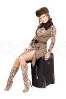 Young lady sits on a suitcase. Isolated