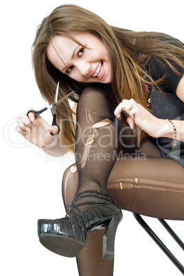 Smiling girl with scissors cuts the stockings. Isolated