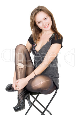 Pretty girl in the torn stockings sits on a chair