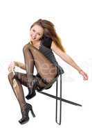 Smiling playful girl in the torn stockings sits on a chair