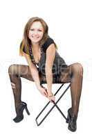 Young woman in the torn stockings sits on a chair. Isolated