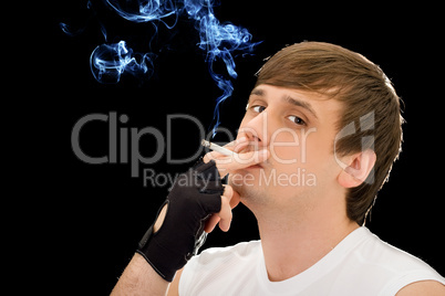 Young man smoking a cigarette. Isolated on black