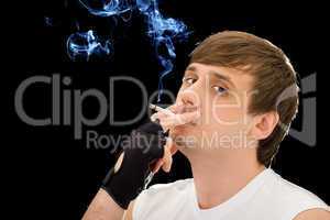Young man smoking a cigarette. Isolated on black