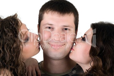 Two beautiful girls kiss the young man