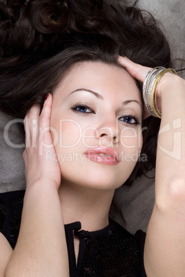 Portrait of the loveky lady lying on grey fur coat