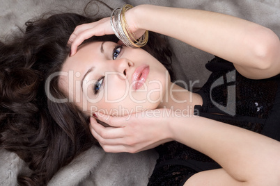 Beautiful girl lying on grey fur coat