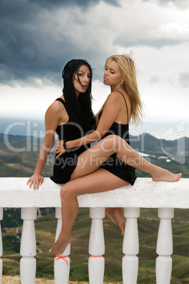 Two sexy young women sitting on a white handrail