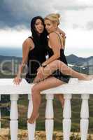 Two girls sitting on a white handrail