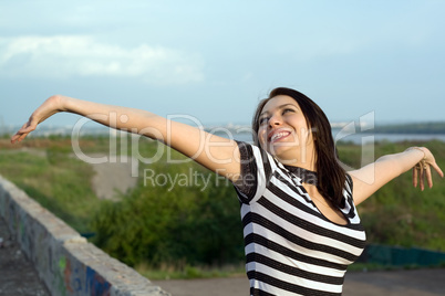 Happy young woman with arms raised outdoors