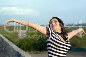 Happy young woman with arms raised outdoors