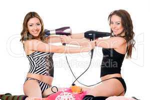 Two playful girlfriends with hair dryers. Isolated