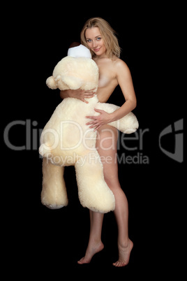 Pretty naked young woman posing with large teddy bear
