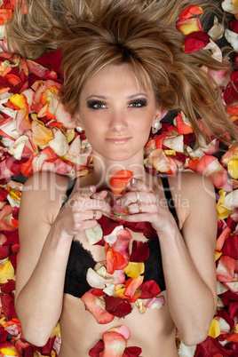 playful young blonde lying in rose petals