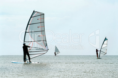 Silhouettes of a three windsurfers