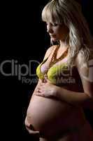 Pregnant young woman in yellow lingerie. Isolated