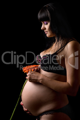 Pregnant young brunette with red flower. Isolated