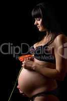 Pregnant young brunette with red flower. Isolated