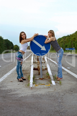 Two pretty girls stand on a road