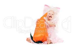 Happy baby girl plays with a carrot