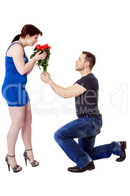 Man kneels in front of the woman and gives her flowers