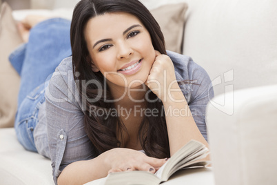 Happy Hispanic Woman Reading Paperback Book at Home
