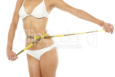 Fit woman measuring her waist, cropped image