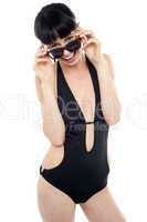 Exotic woman in black bikini peeking through her sunglasses