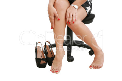 Businesswoman wearing high heels shoes, sitting and massaging ti