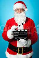 Bespectacled Santa holding a clapperboard