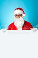 Aged Santa standing behind a blank ad board