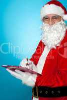 Santa Claus making notes in the wish list