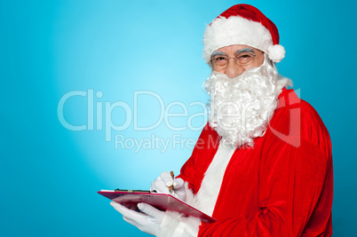 A thoroughly modern Santa claus checks his list on clipboard